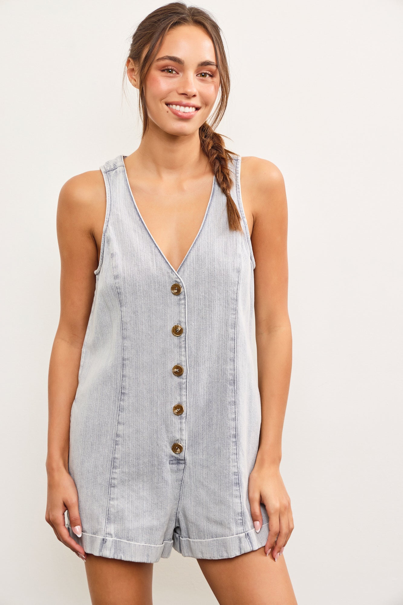 Model wearing sleeveless V-neck light denim romper with button front
