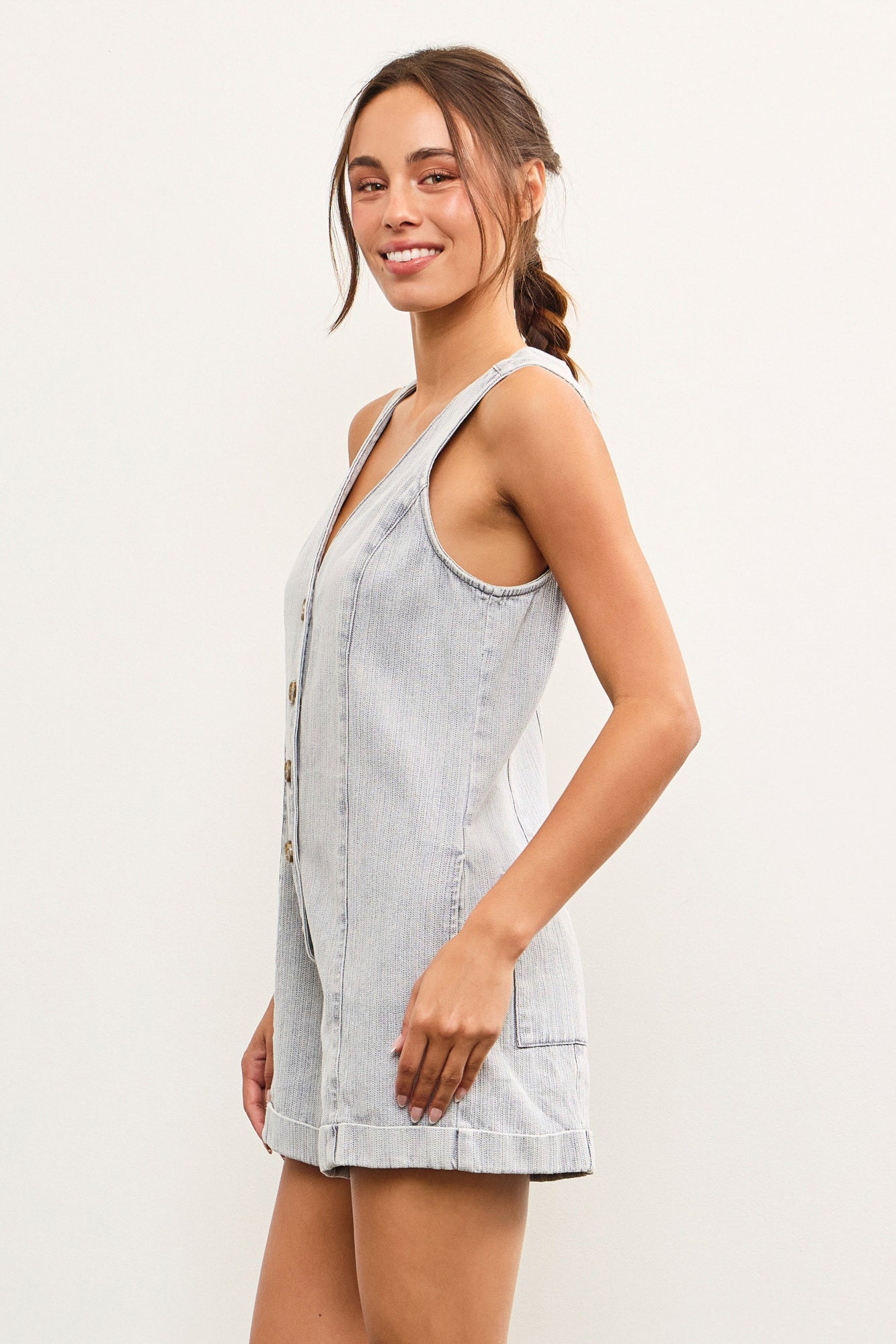Model wearing sleeveless V-neck light denim romper with button front