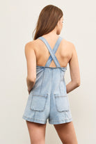 Back view showing crossed straps and patch pockets on the romper.
