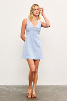 Model wearing blue checkered sleeveless mini dress with lace trim and tie front